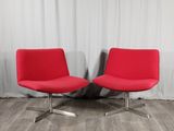 une paire de chaises rouges devant un rideau blanc, sur un parquet