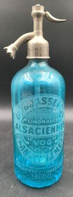 une vieille bouteille en verre bleu avec une poignée en métal, posée sur une table