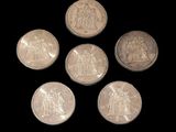 six pièces d'argent sont disposées en cercle sur un fond noir