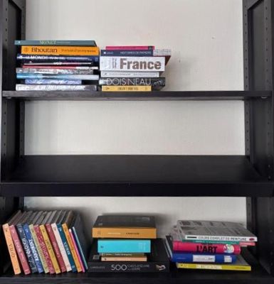 une bibliothèque noire sur laquelle sont posés de nombreux livres