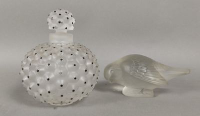 une bouteille en verre sur laquelle est représenté un oiseau, à côté d'une autre bouteille en verre sur laquelle est représenté un oiseau