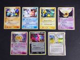 Plusieurs cartes Pokémon sont alignées sur une surface noire