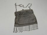 silver mesh purse with chain handles and fringes on a white surface