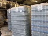several stacks of plastic water bottles stacked on pallets in a warehouse