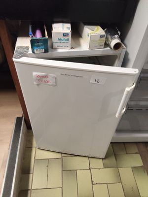 a small white refrigerator in the corner of a kitchen