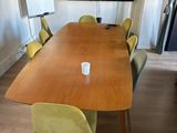 a long wooden table with green chairs and a flat screen tv on the wall