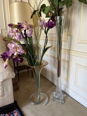 two tall vases with flowers in them on the floor