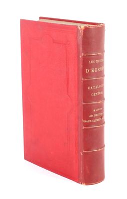 un livre rouge posé sur une table à côté d'un mur blanc