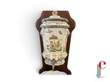 a vase on a stand with a bird and flowers on it