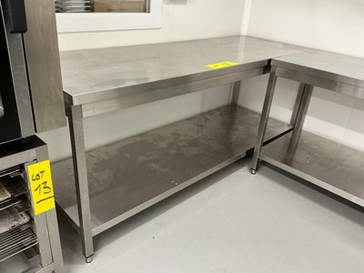 un plan de travail en acier inoxydable dans une cuisine, sur lequel est posé un micro-ondes