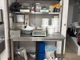une cuisine avec des étagères en inox et beaucoup de vaisselle sur le plan de travail
