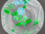 un cendrier en verre orné d'une fleur bleue
