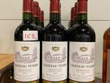 quatre bouteilles de vin sont alignées sur un comptoir, à côté d'une bouteille de vin