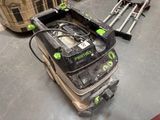 a green and black duster on the floor next to a suitcase