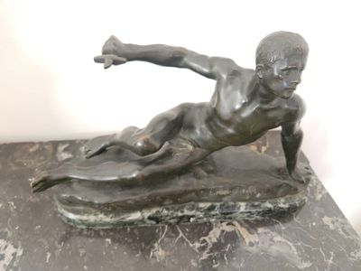 statue représentant un garçon sur une planche de surf, posée sur un socle en marbre