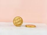 a gold coin sitting on top of a white table next to a pink wall