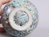 a person holding a glass ball with a mosaic design on it