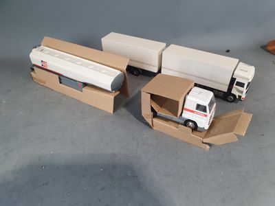 two toy trucks that are sitting in a cardboard box