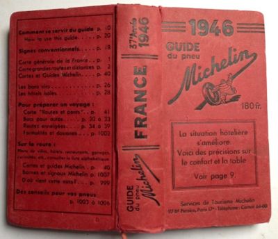 an old book with a red cover sitting on top of a table