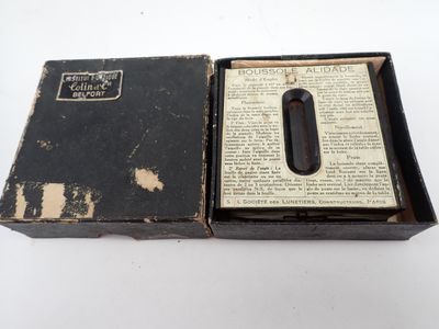 une vieille boîte noire contenant un livre ouvert, posée sur une surface blanche