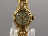 a gold wrist watch on display on a clear stand