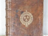 un livre en cuir marron orné d'un emblème doré