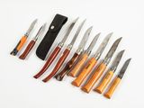 sept types de couteaux différents et un étui posés sur la table