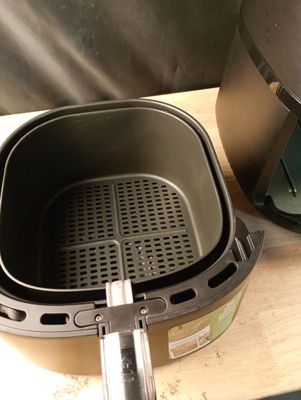 une friteuse à air chaud posée sur un plan de travail, à côté d'une poêle
