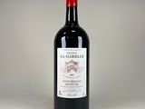 bottle of red wine with a red cap sitting on a white surface