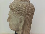 sculpture of a head of a buddha on a black stand