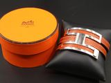 une boîte orange ornée d'une boucle argentée, posée à côté d'un oreiller noir