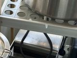 Les casseroles et les poêles sont rangées sur une étagère dans une cuisine, à côté d'une cuisinière.