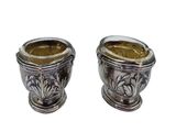 two silver vases sitting next to each other on a white surface