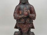 une vieille statue en bois d'un homme avec un chapeau sur la tête