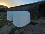 two large white bales sitting in front of a barn