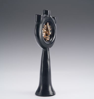 a black vase with a face in the middle of it