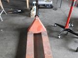 un chariot élévateur dans un garage, avec d'autres outils en arrière-plan