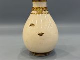 a white vase with a gold decoration on it