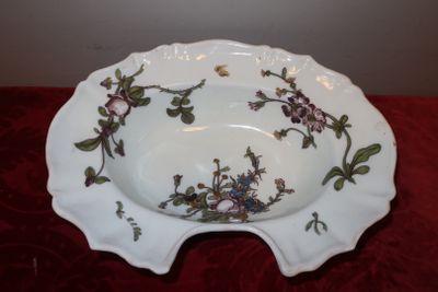un bol blanc orné de fleurs, posé sur une table rouge