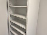 an open white bookcase in a room with a carpeted floor