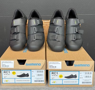 trois paires de chaussures de route Shimano dans leurs boîtes, posées sur une table
