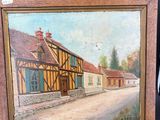 une peinture à l'huile représentant une scène de village, posée sur un chevalet en bois