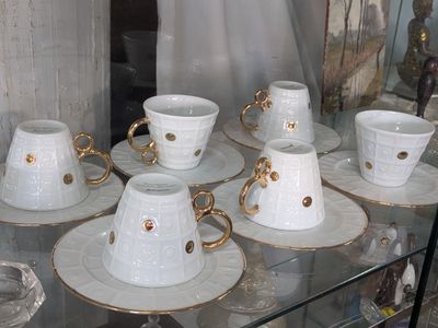 many cups and saucers sitting on a glass shelf