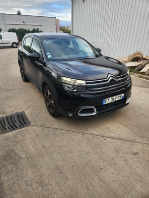 La voiture noire est garée devant un immeuble blanc.