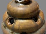 a brown vase with holes in it sitting on a table