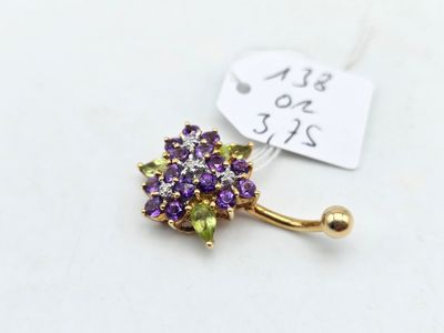 a close up of a purple and green flower on a gold plated belly ring