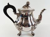 a silver teapot with a black handle on a white background