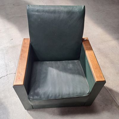 un fauteuil en cuir vert avec une structure en bois, posé à même le sol