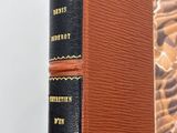an old book sitting on top of a wooden table next to a wall