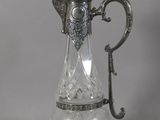 an antique silver plated glass pitcher with a handle on a table